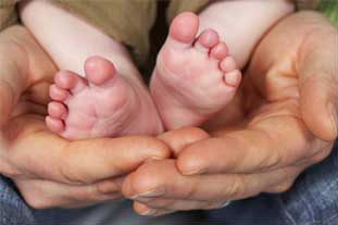 baby feet resting in adult hands