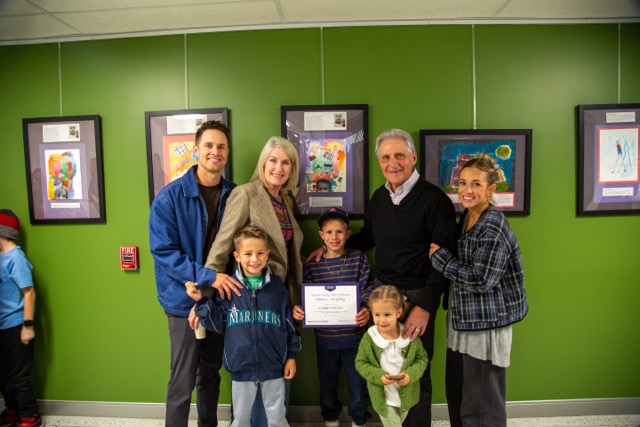 Family poses with child in front of artwork.