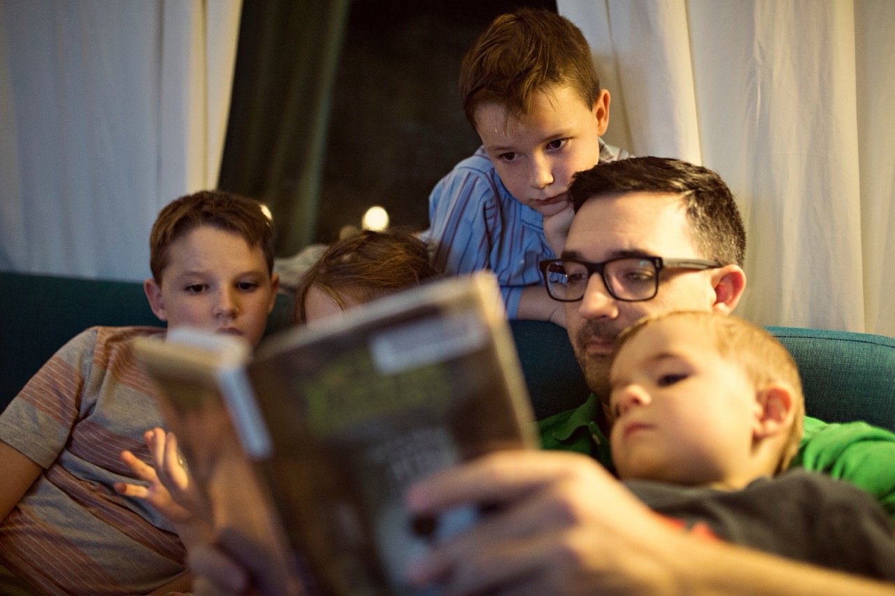 A man reading a book to children