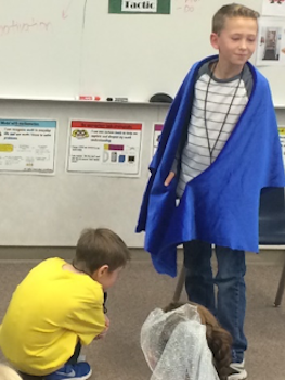 Boy standing with blue cape on. 