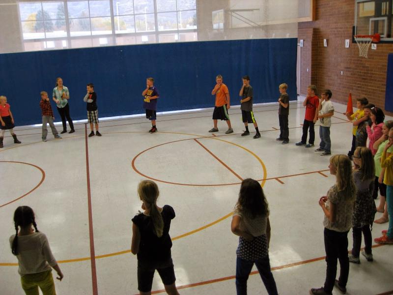 class of young students standing in a circle on a basketball court