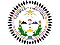 A seal of the Navajo Nation with icons of mountains, a sun, a horse, a sheep, a cow, and two corn crops on the bottom.