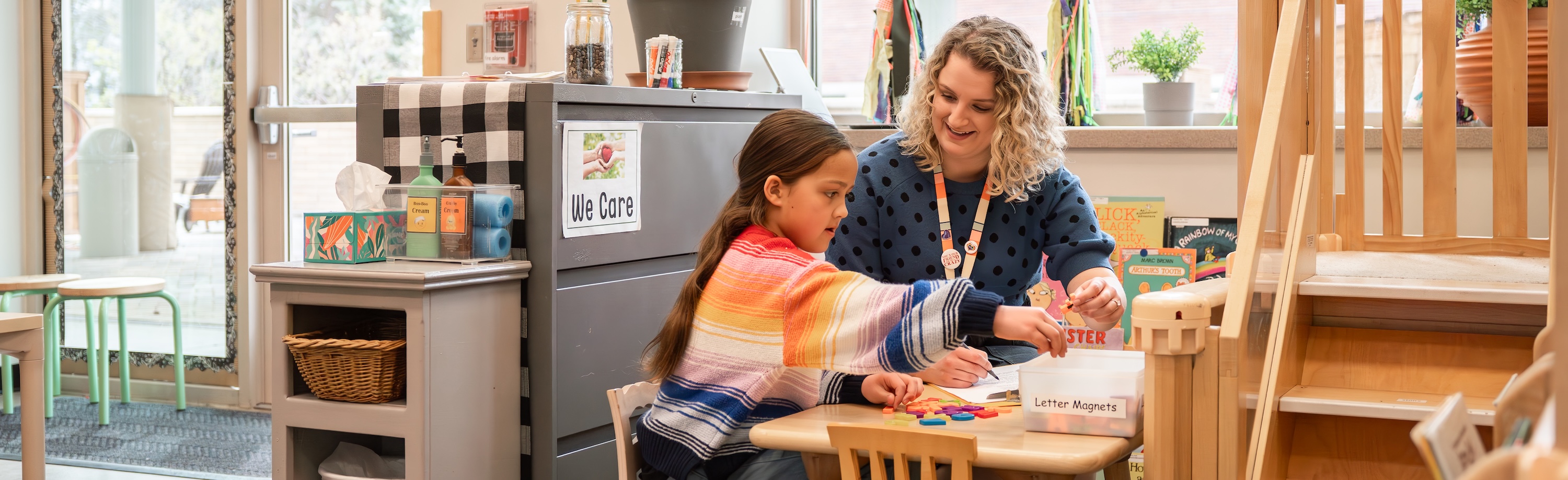 teacher helping child in classroom