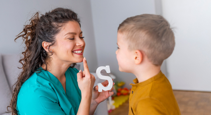 woman teaching a child to say the letter s
