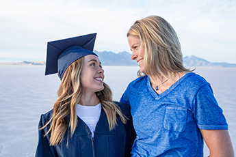 woman in blue graduation robes stands with her mother