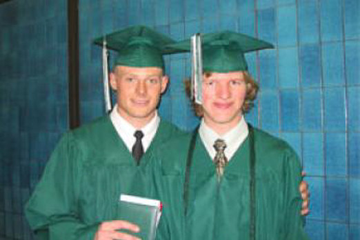 Two people graduating wearing green cap and gowns