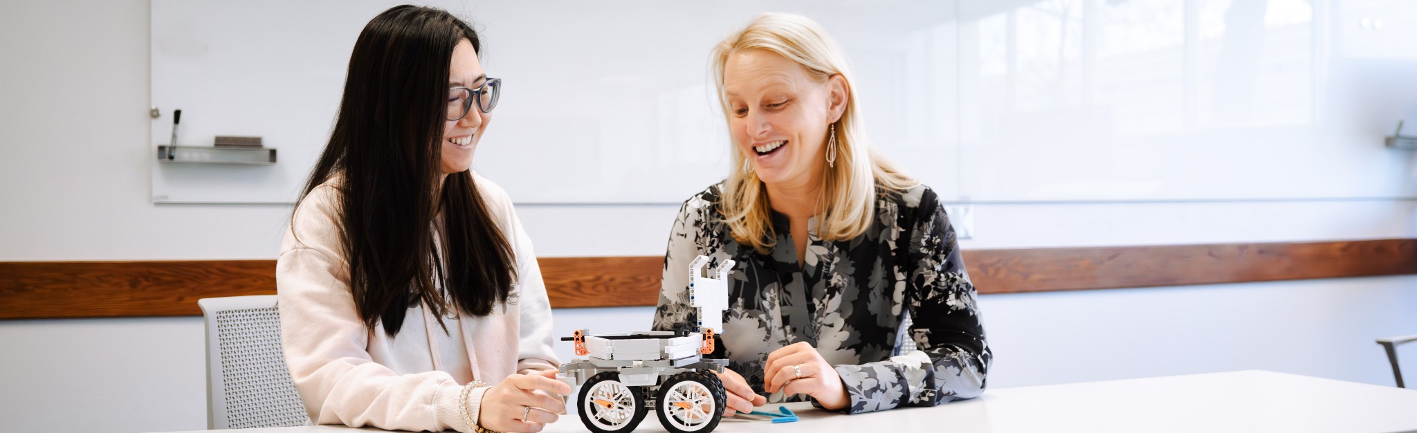 Two women teaching using a small robot on a small table