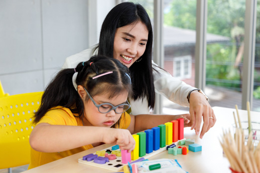 Woman helping child play with blocks