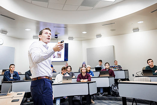 a professor points to the board as he instructs a class