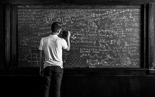 a student writes math equations on a chalkboard