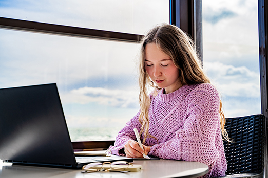 a woman in a pink sweater studies in a university library