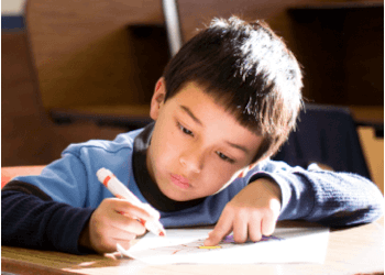 child drawing at a desk