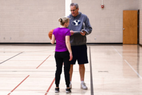 coach helping female basketball player