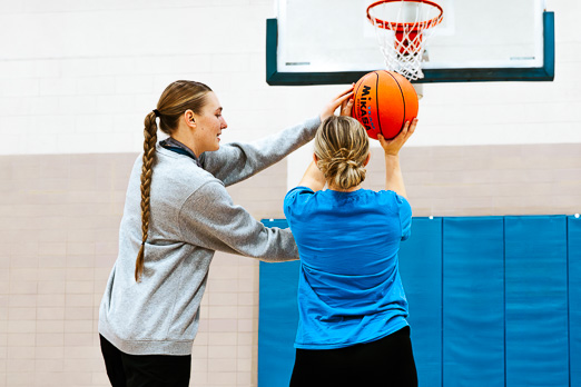 Coach showing a young girl how to shoot a basketball