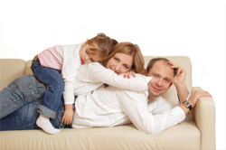 girl lying on top of woman and man on couch