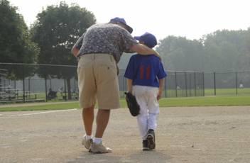 man walking with boy on a baseball field