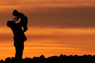 man and boy in front of sunset