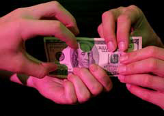 four hands holding a dollar bill
