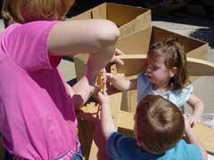 woman, boy, and girl taping cardboard boxes