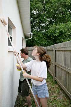 woman and man painting an exterior house wall