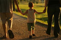 boy walking while holding hands of man and woman