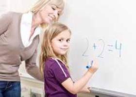 girl writing math on a whiteboard with help from woman