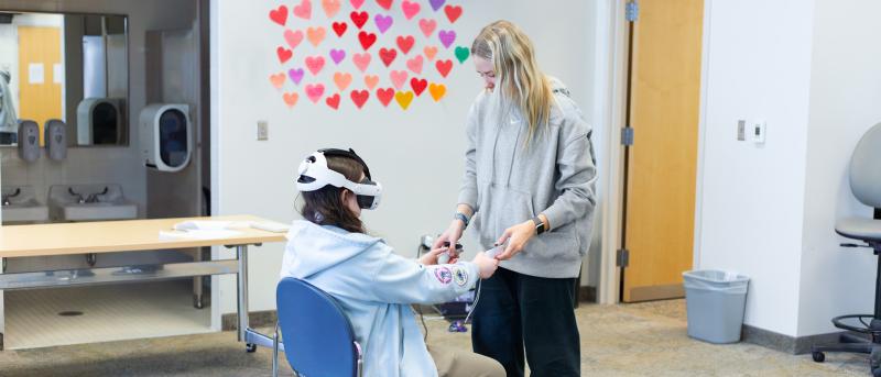 a woman helping a girl set up the Virtual reality headset