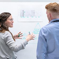 two people discussing things on a whiteboard