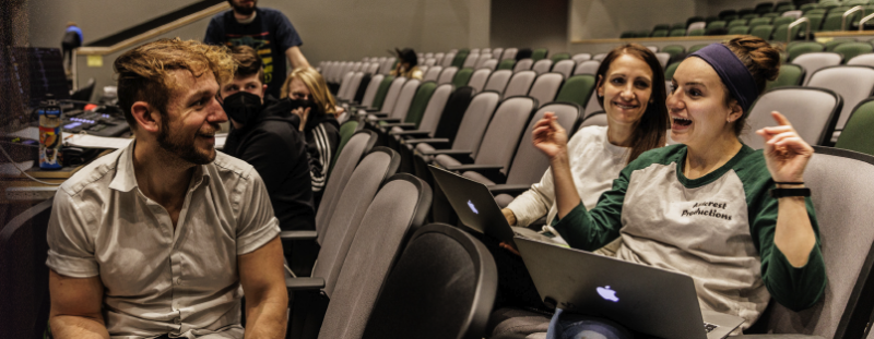 Giselle Gremmert and Joshua Long talking while sitting in the theater audience