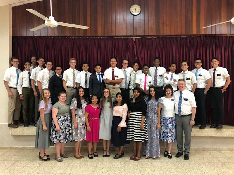 A group of missionaries stands in a church cultural hall.