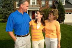 man and woman standing in front of house with younger woman