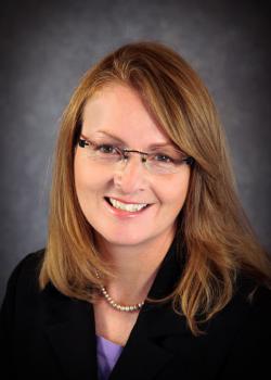 Picture of a woman (Terisa Gabrielsen) wearing a black blazer and a purple shirt smiling at the camera.