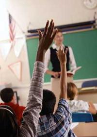 students raising hands in a classroom
