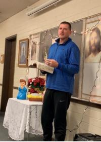 Steve Christensen reading scriptures in a Church building with Christmas decorations behind him