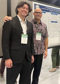 Presenters standing next to scholarly poster.