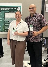 Presenters standing next to scholarly poster.